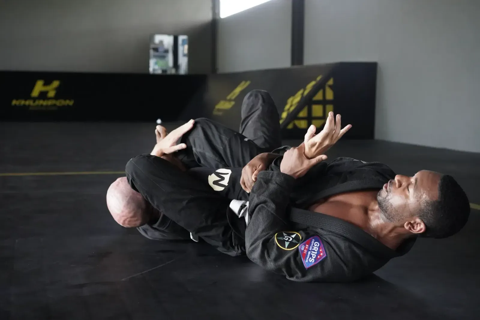Two grapplers drilling a gi choke on the mats