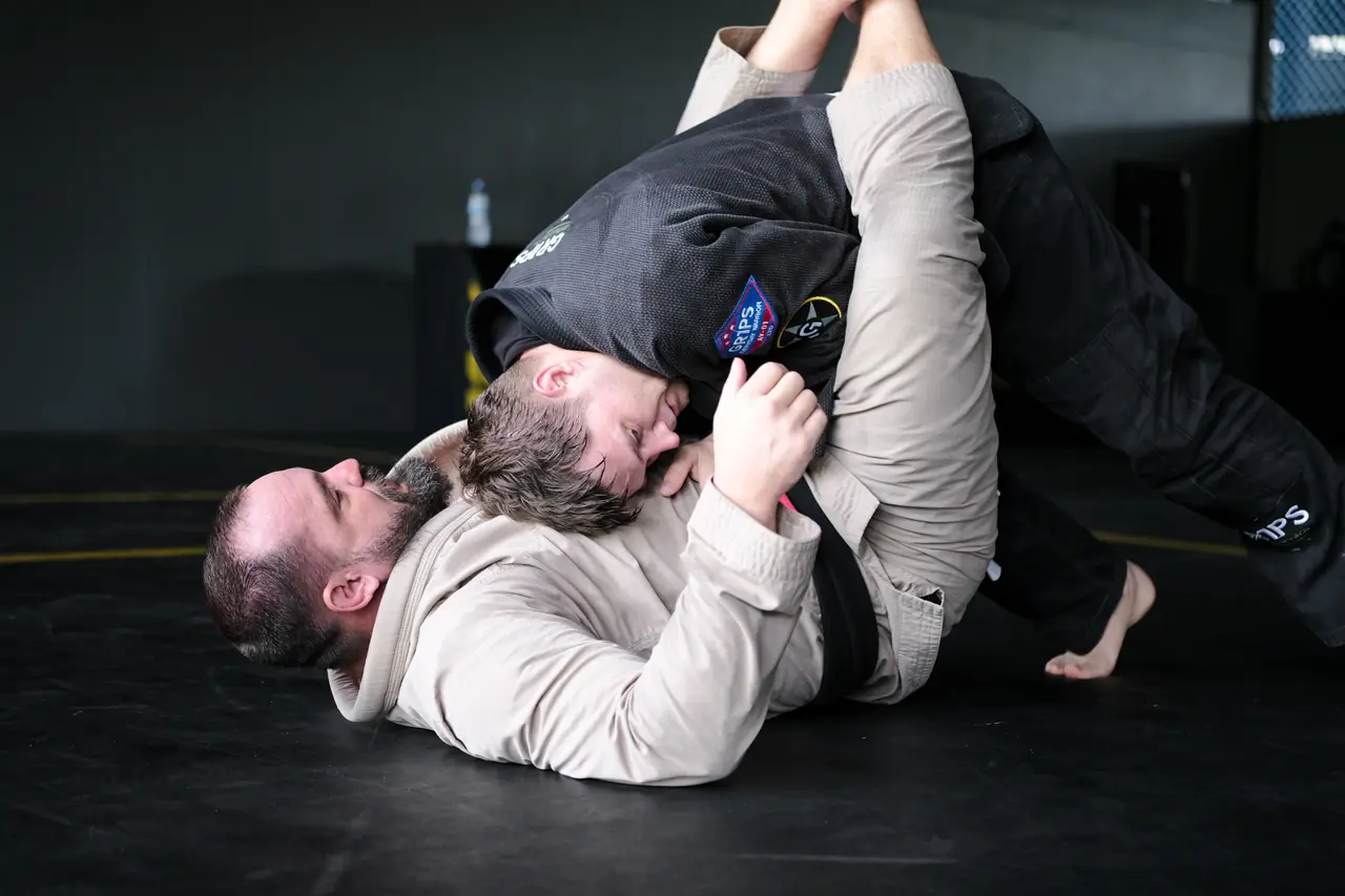 A student in a gi controls his partner from behind during a round
