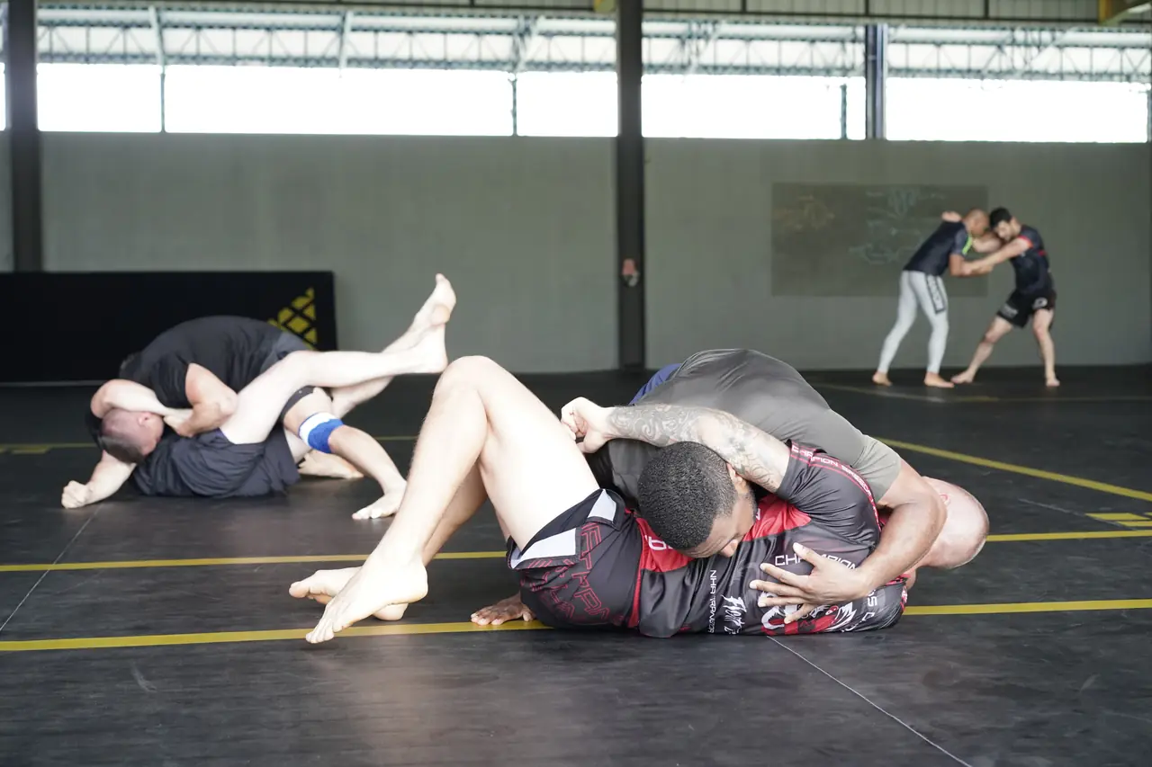 Several pairs of No-Gi grapplers roll at the same time on the Khunpon mats
