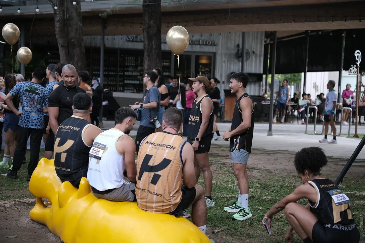 Khunpon crew members relaxing on and around a yellow bench after the run