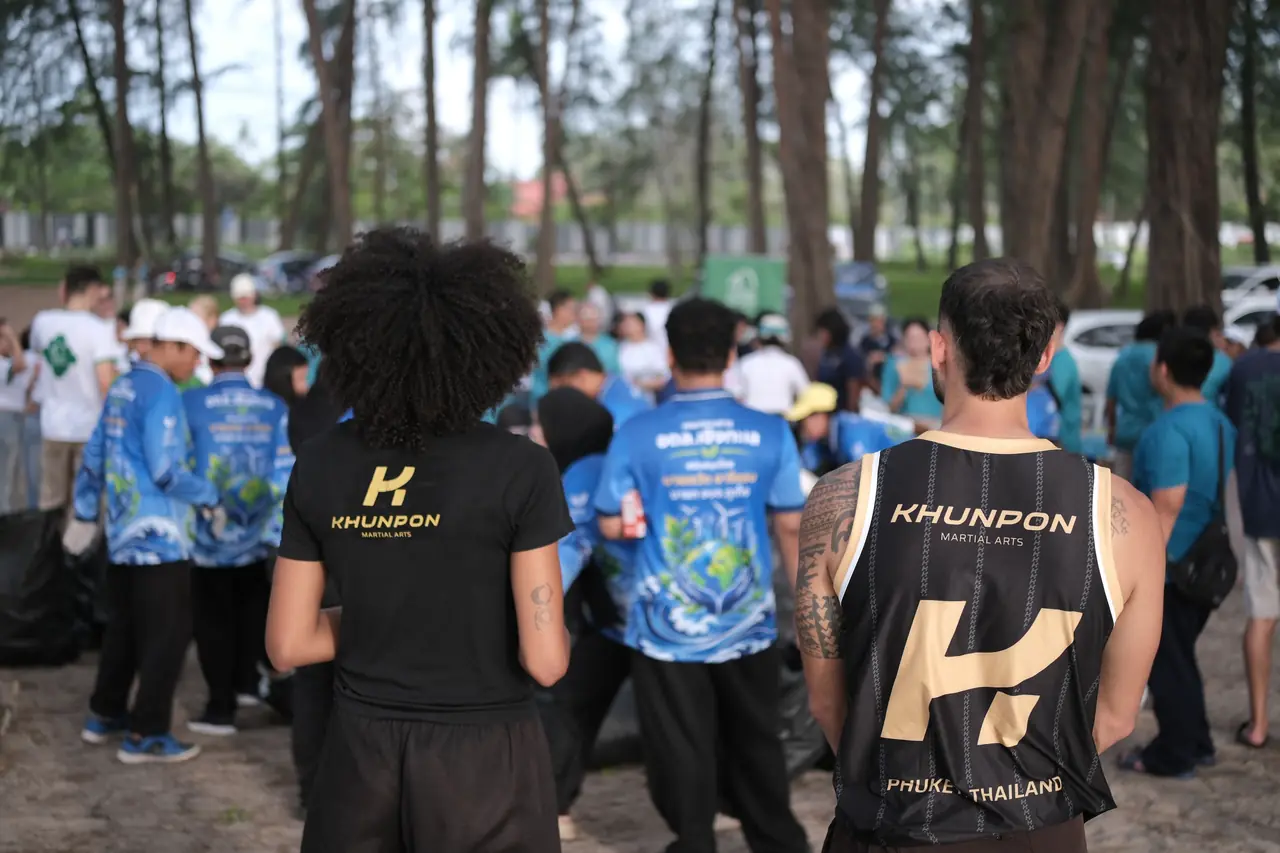 Khunpon crew members in their gym shirts among the volunteers gathering under the trees at Layan Beach
