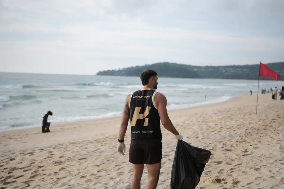 A Khunpon crew member with a rubbish bag at the water's edge