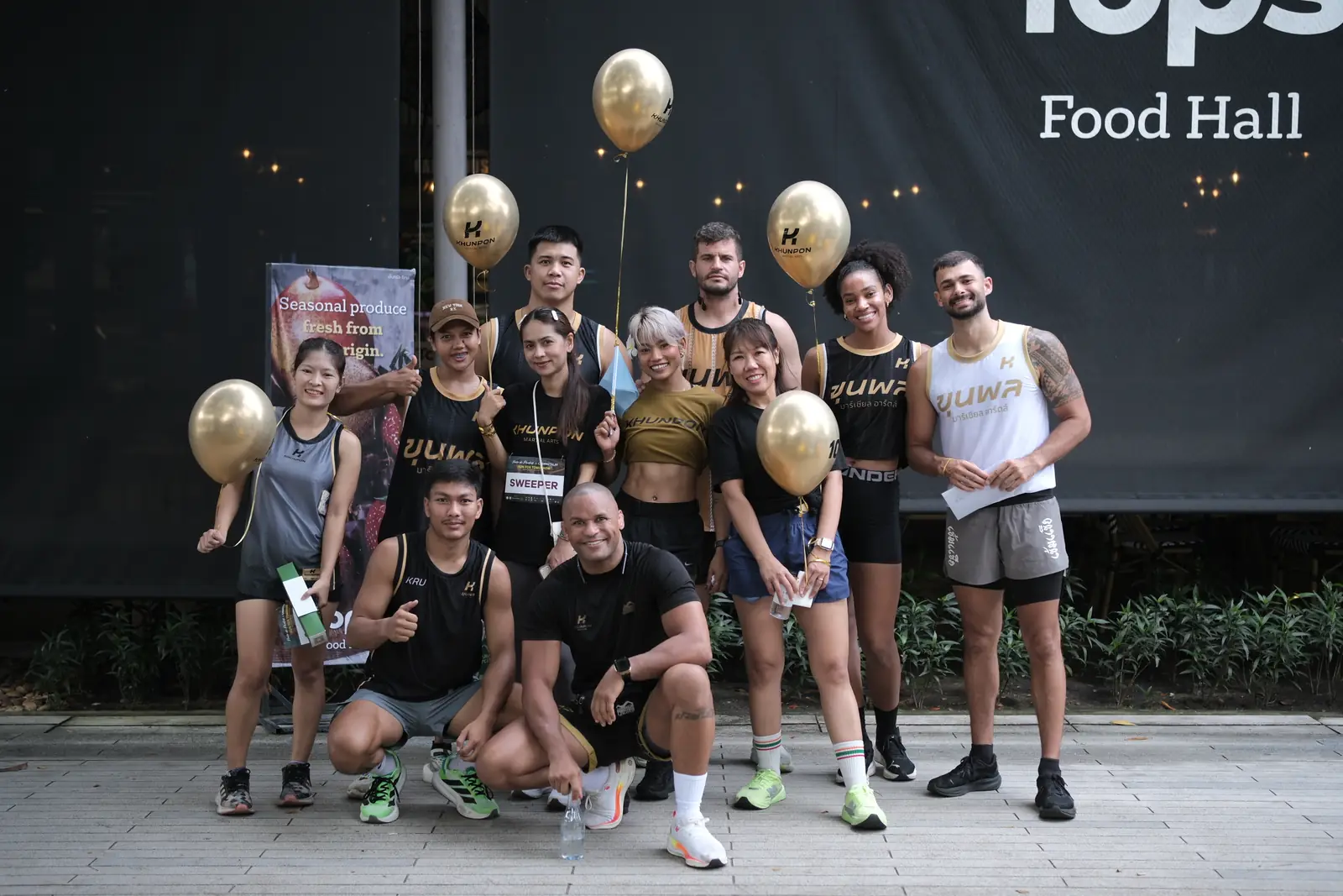 Khunpon Martial Arts crew members with gold balloons outside Tops Food Hall at Porto de Phuket before the Run for Tomorrow