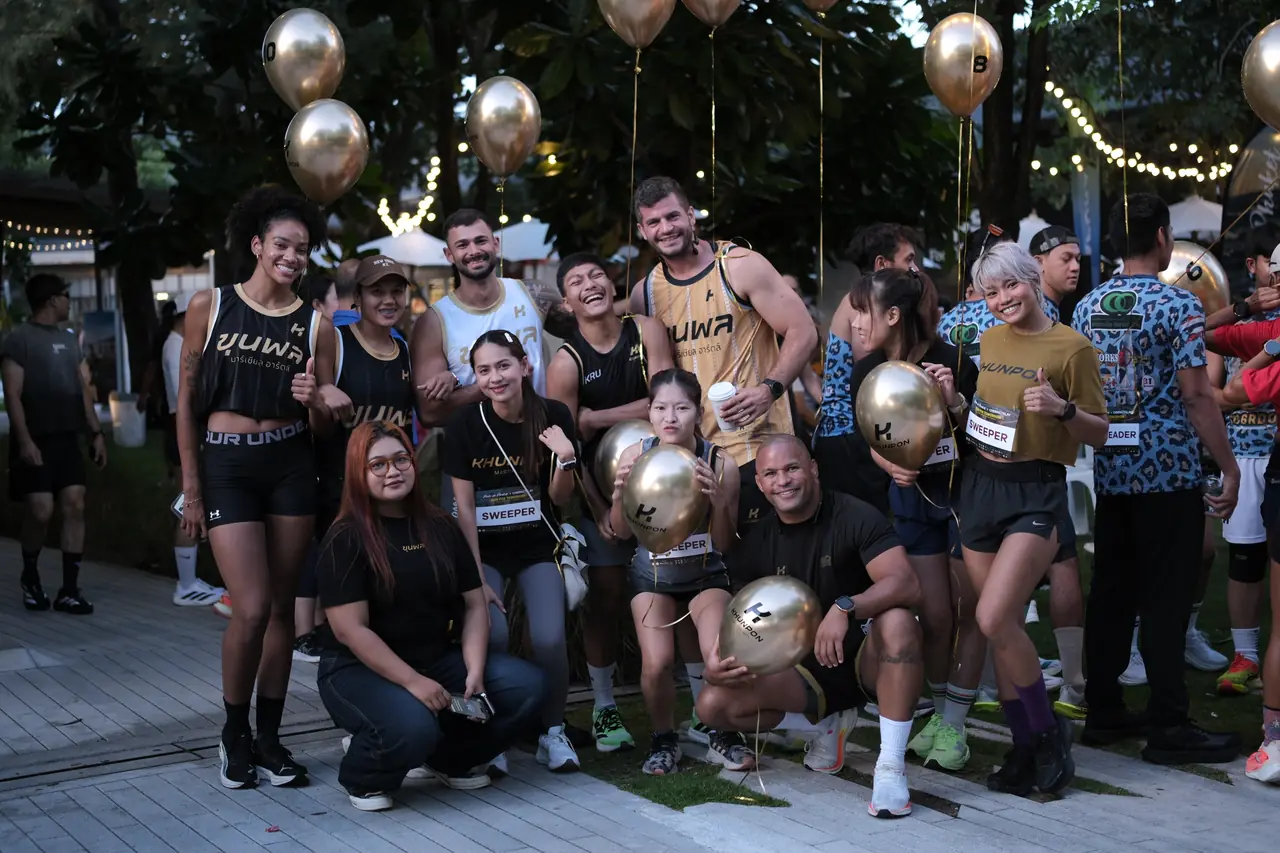 Khunpon's crew and fellow runners holding gold balloons together after the run