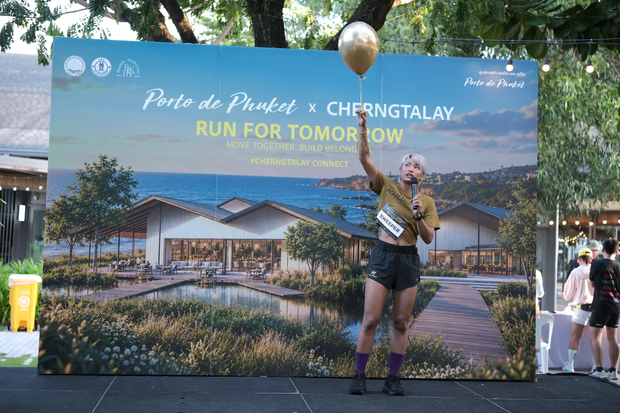 A host on stage in front of the Porto de Phuket x Cherngtalay Run for Tomorrow backdrop