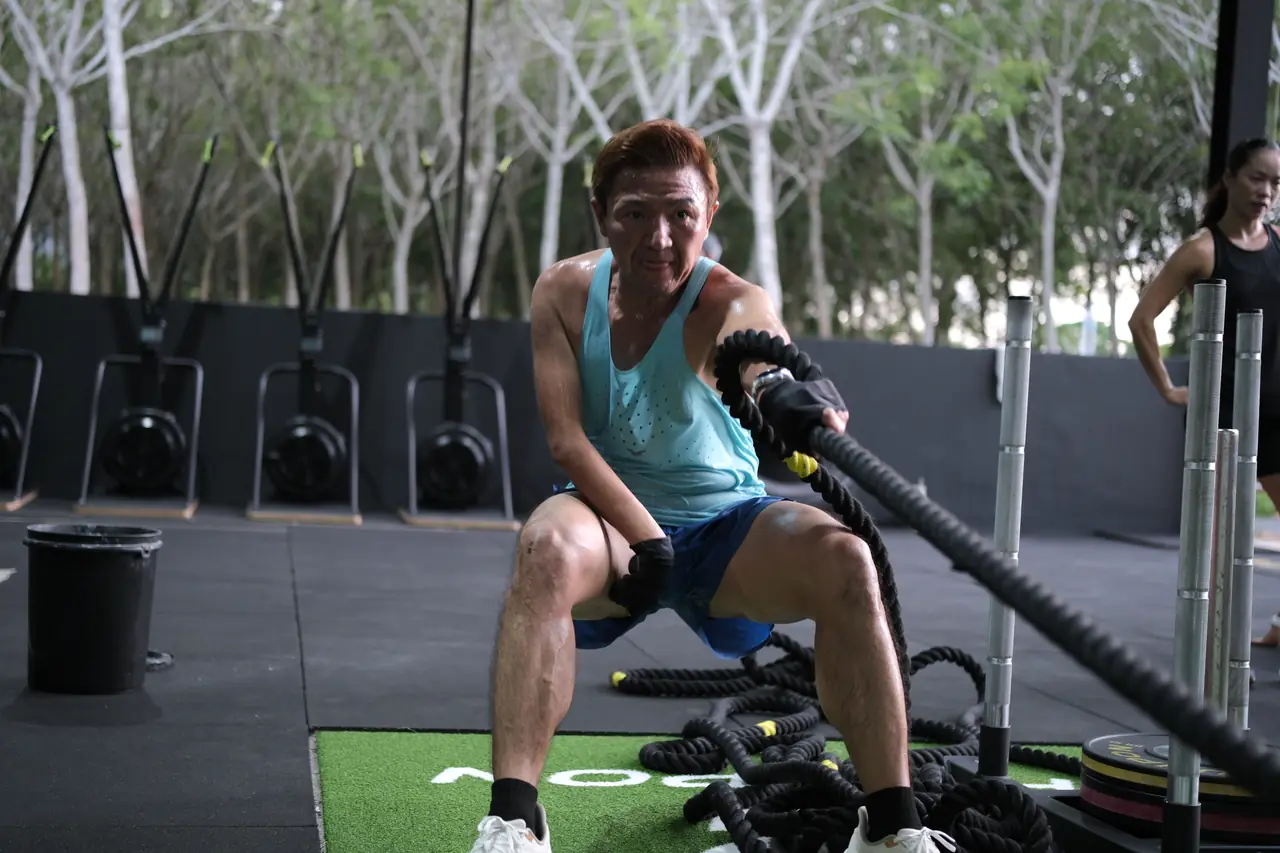 A member pulls a battle rope on the turf during a fitness class