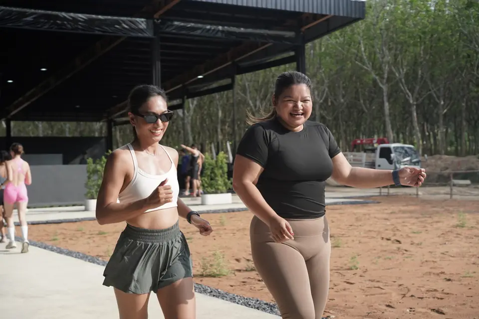 Two women walk into the gym smiling before their heat