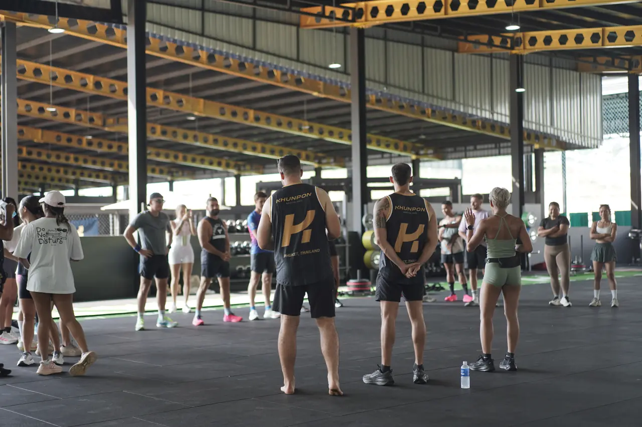 Athletes gather on the gym floor for the briefing before the first heat, two of them in Khunpon shirts