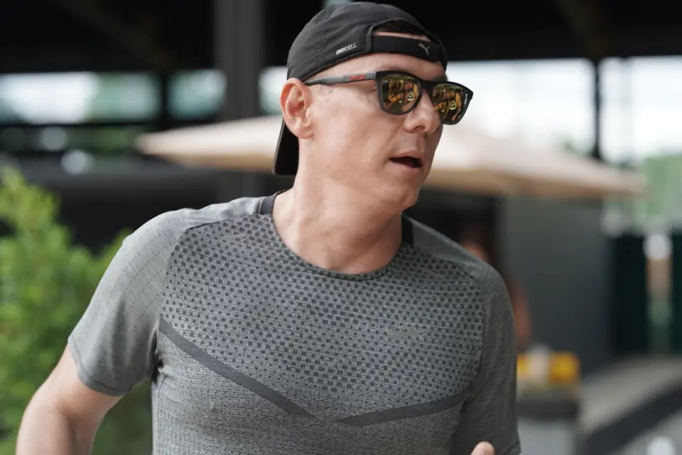 A coach in a cap and sunglasses watches the course