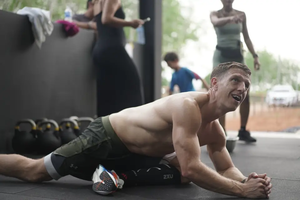 An athlete lies on the floor grinning after his heat
