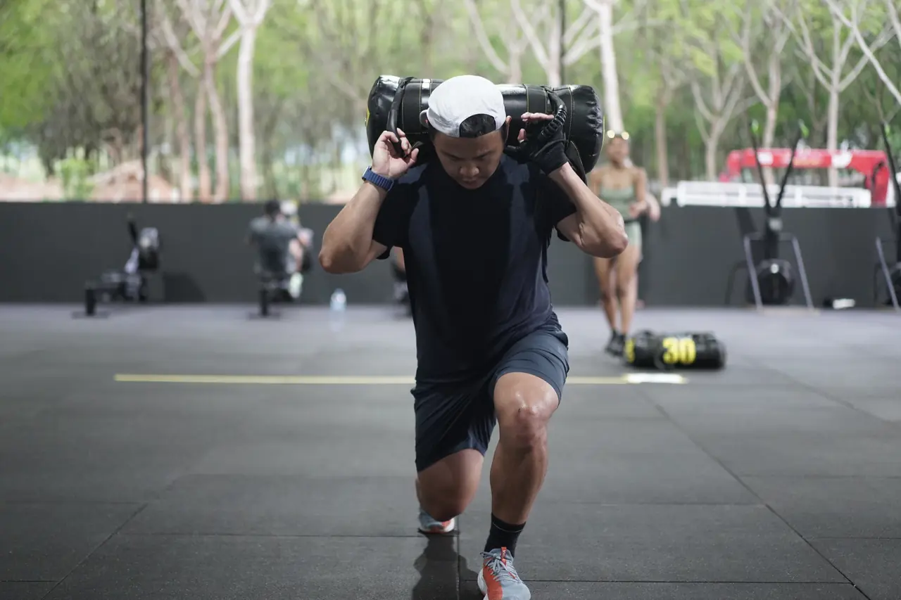 A man walks the lunge station with a sandbag across his shoulders