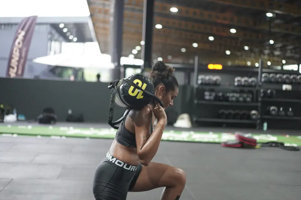 A woman lunges with a sandbag on her shoulders