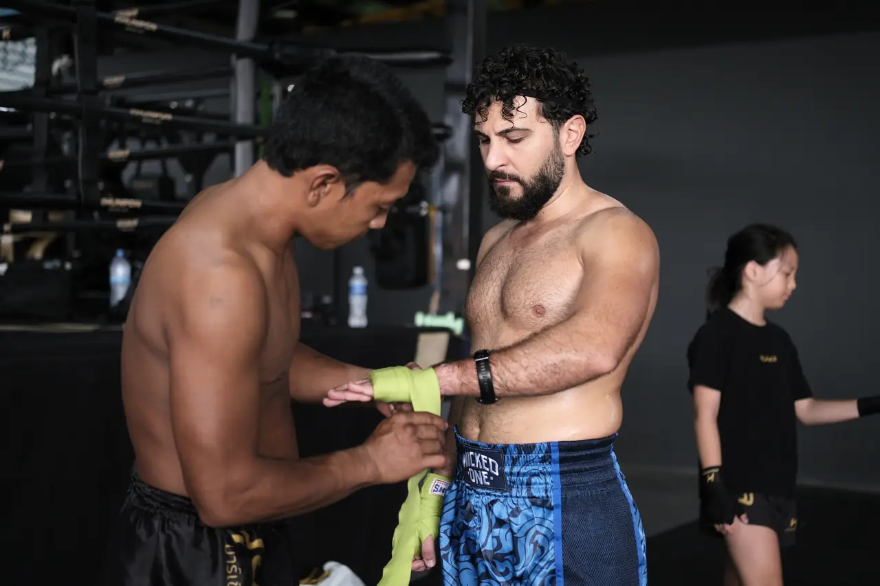 A Thai coach wraps a student's hands before a Muay Thai class at Khunpon