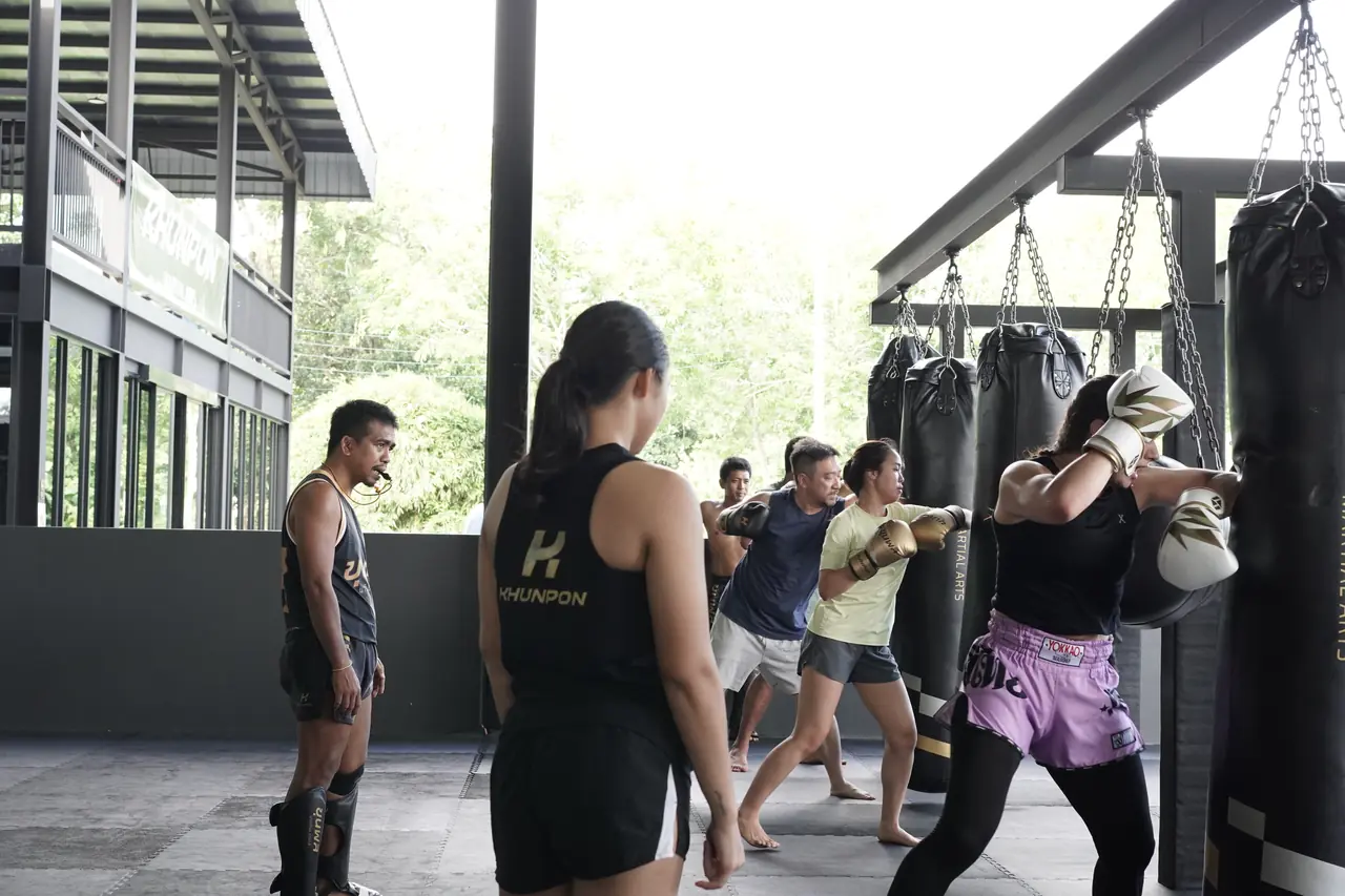 A coach watches students work the heavy bags at Khunpon