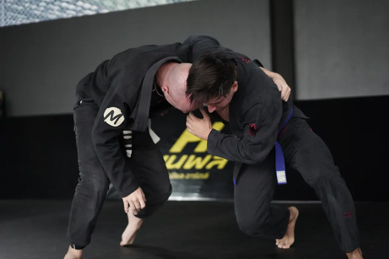 Two students in gis clinch and fight for position during a BJJ class