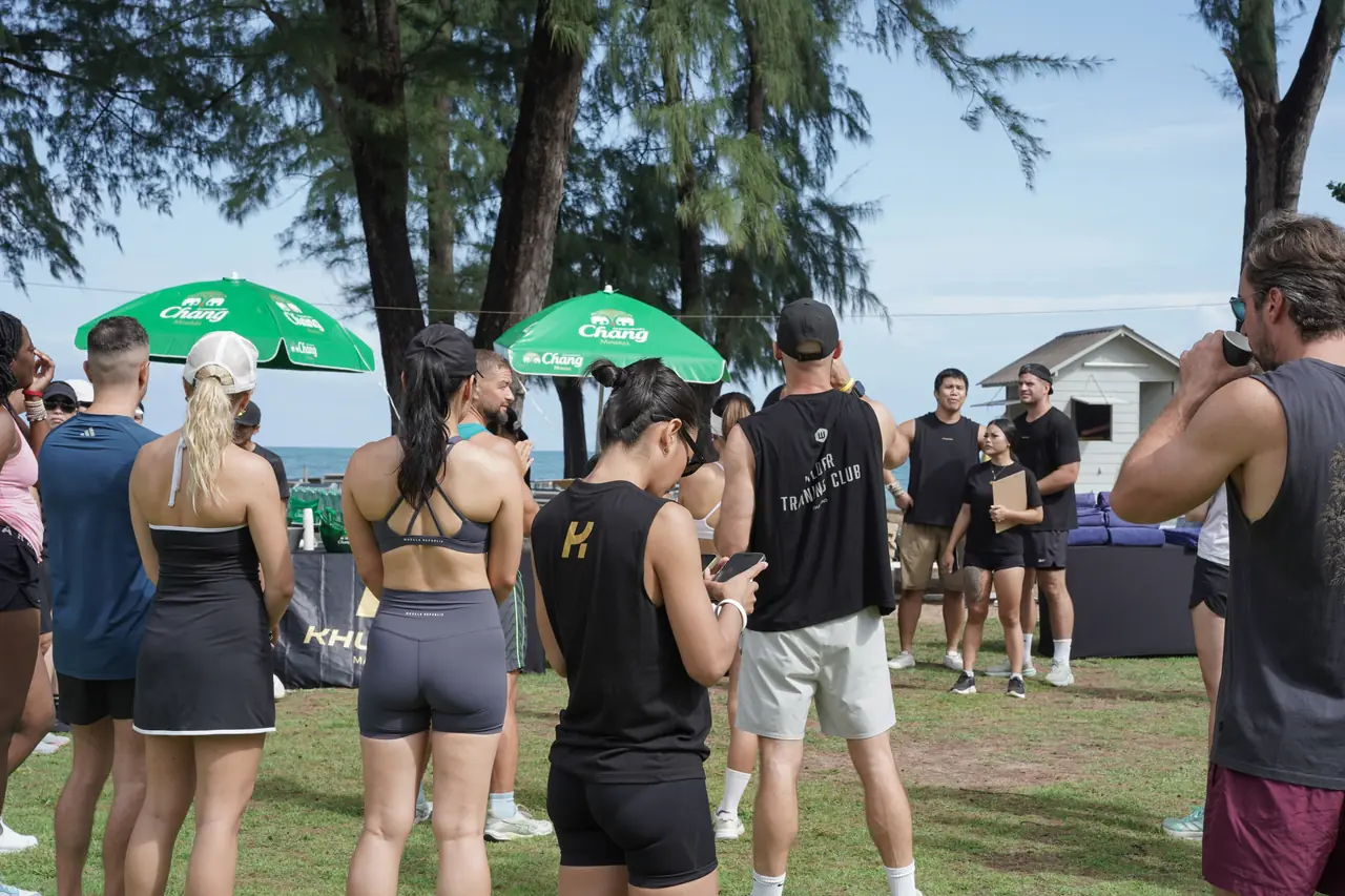 Competitors gather for the briefing under the trees at Amora Beach Resort, with the sea behind them