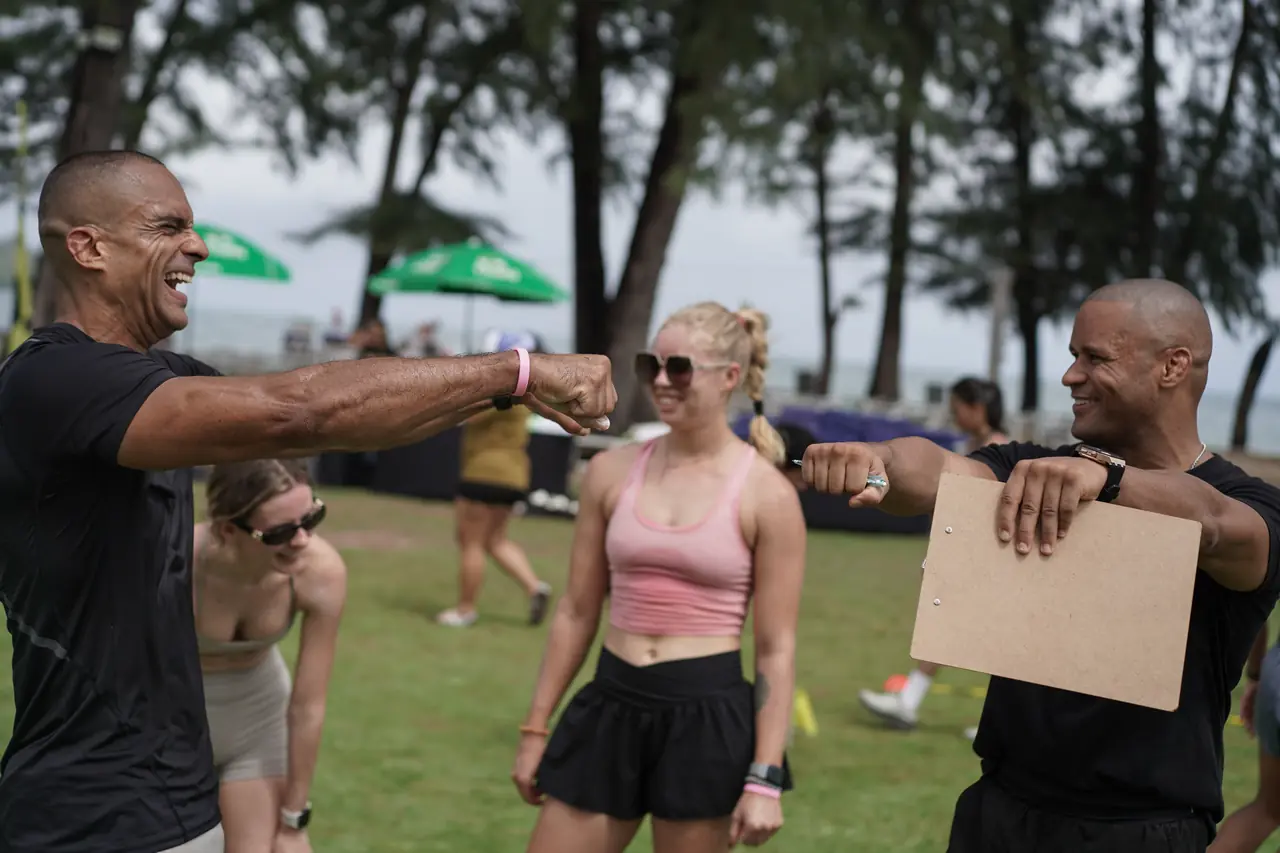 A Khunpon coach with a scoring clipboard shares a fist bump with a competitor