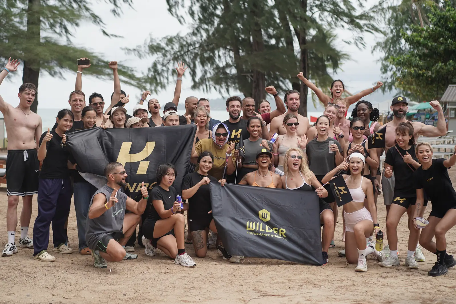 HYROX by the Beach competitors and Khunpon coaches on Bang Tao Beach with Khunpon and WILDER banners