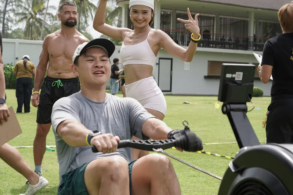A competitor rows while a teammate cheers behind him