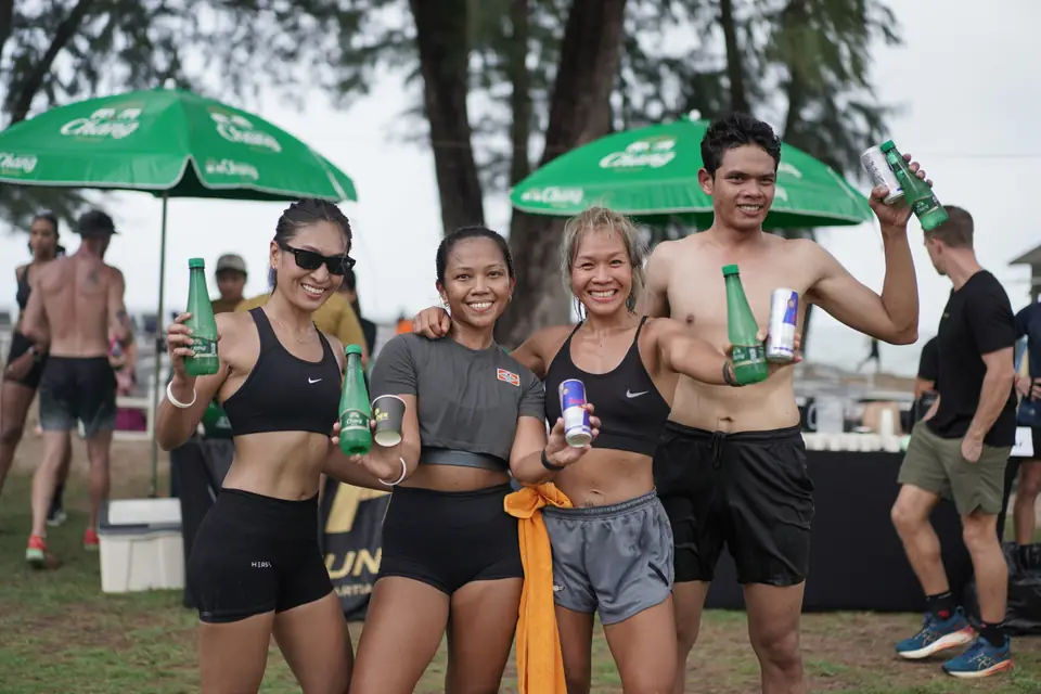 Four teammates raise bottles of Chang water and cans of Red Bull