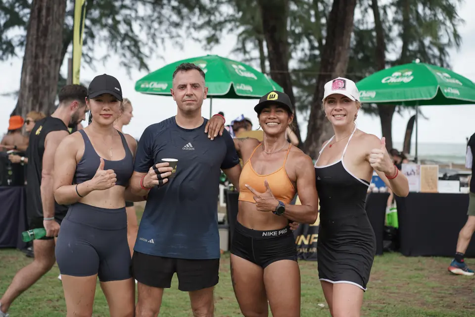 A team of four give thumbs up in front of the partner tents
