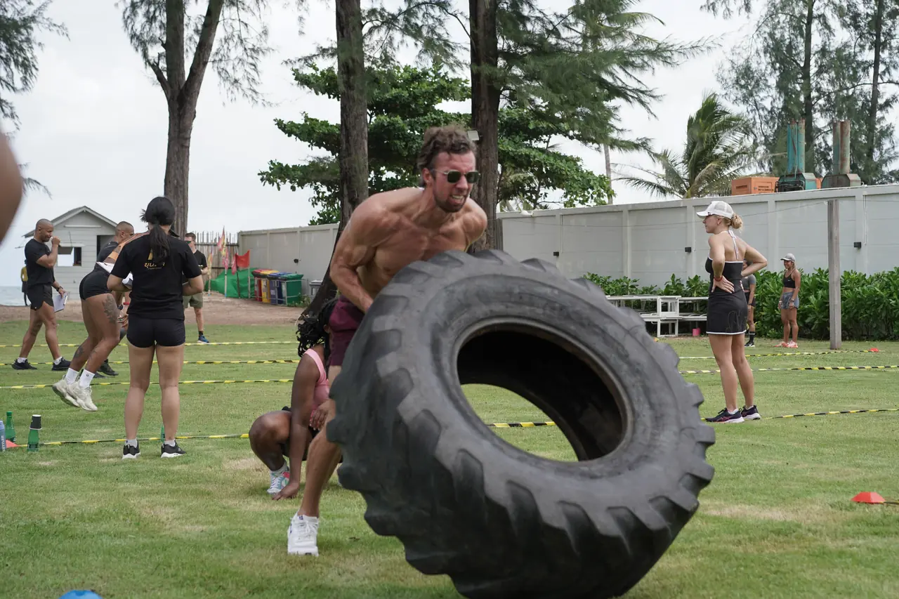 A competitor flips a tractor tyre on the lawn at Amora Beach Resort