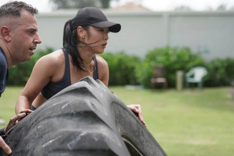 Two teammates flip a tyre together