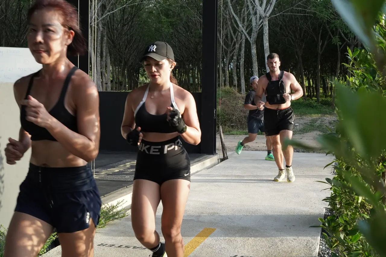 Members run outside the gym along the tree-lined path during a session