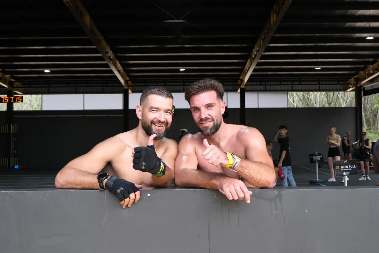 Two competitors lean on the barrier and grin after finishing
