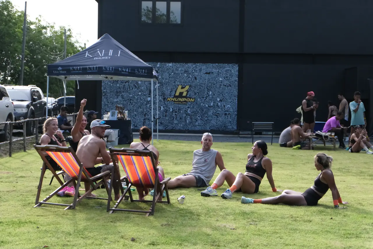 Participants relax in deckchairs and on the grass beside the gym between heats
