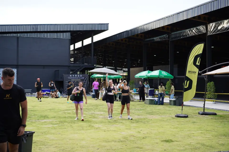 The lawn beside the gym with sponsor tents and people resting in the shade