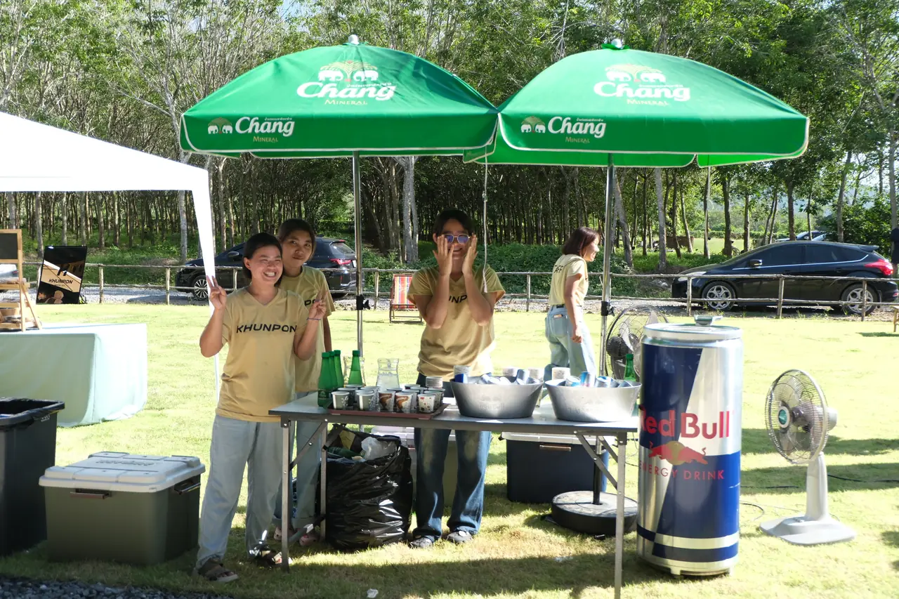 Khunpon staff at the Chang and Red Bull refreshment table under green Chang umbrellas