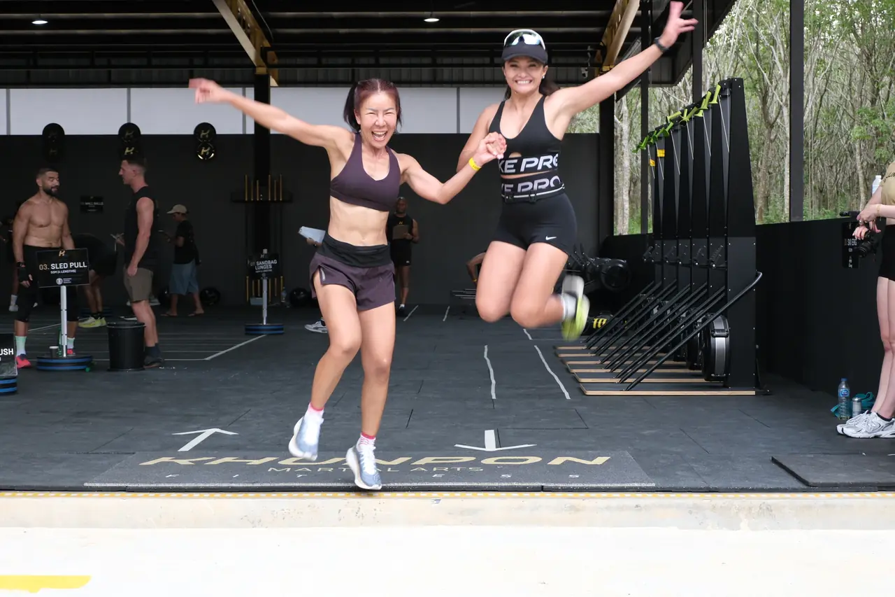 Two relay teammates leap into the air together at the finish