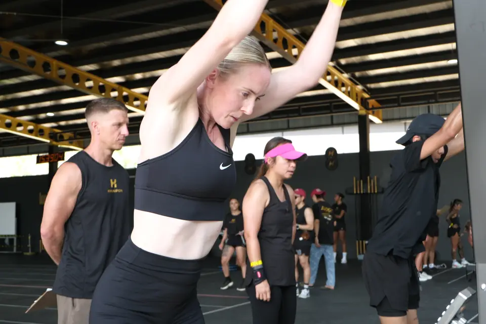 A woman pulls the SkiErg handles down with her eyes closed in effort