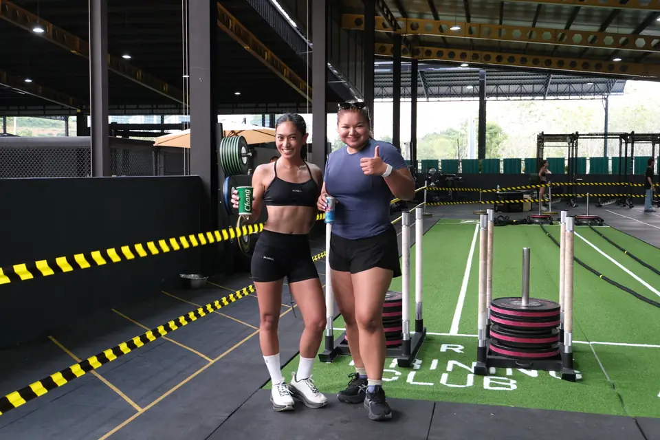 Two women give thumbs up in front of the sled lanes