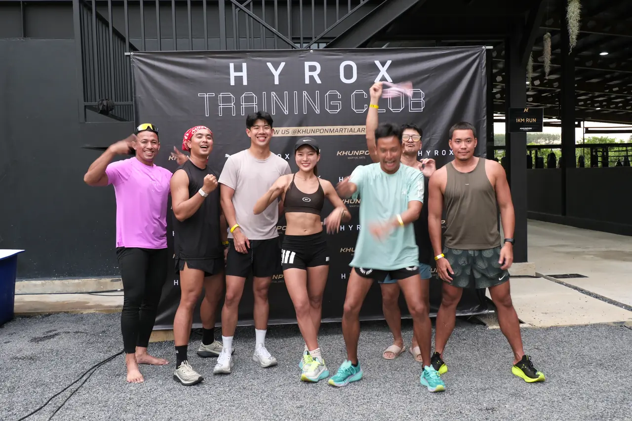 Six participants pose in front of the HYROX Training Club banner after the event