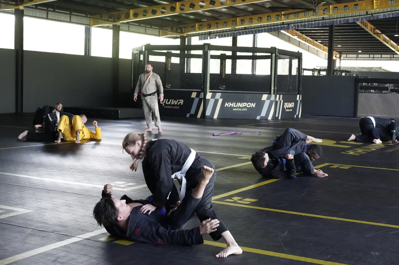 The octagonal cage stands at the end of the mat hall behind students rolling in gis