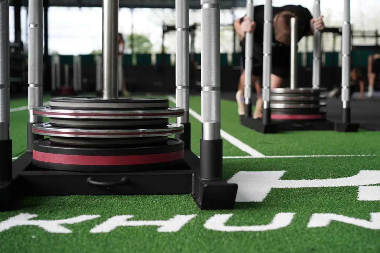 Weight plates stacked on a sled on the turf, ready for a HYROX session