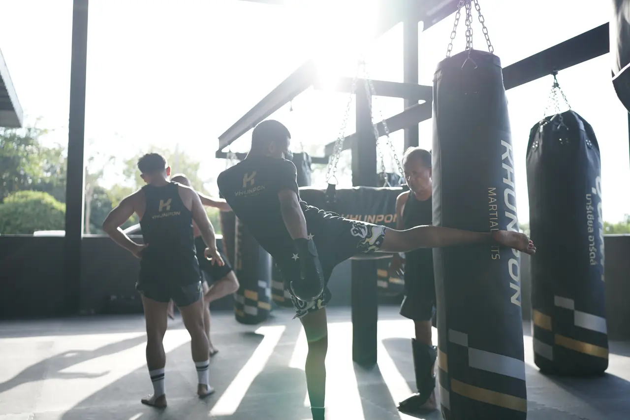 Sunlight pours across the Khunpon bag area as members kick heavy bags in the late afternoon