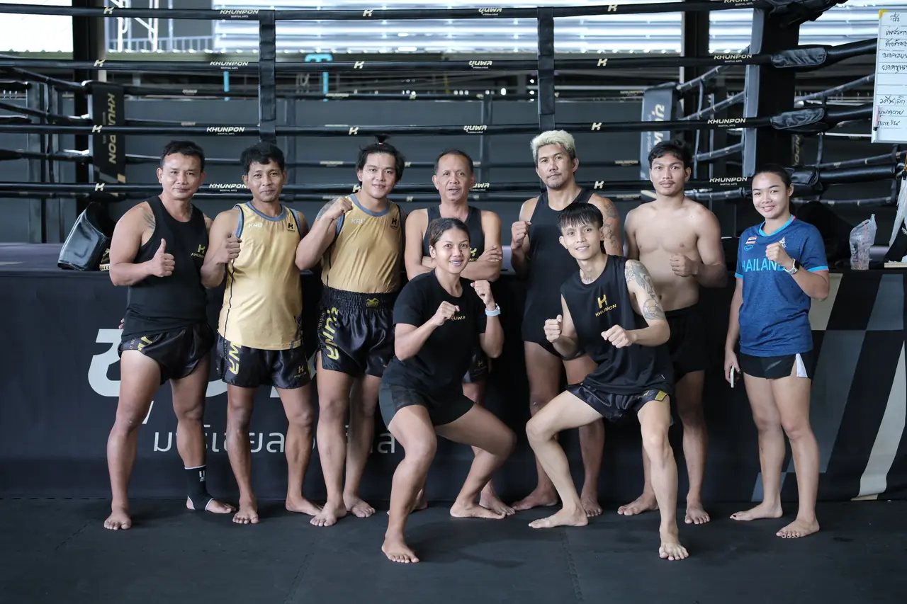 The Khunpon Muay Thai team lines up together in the gym, thumbs up