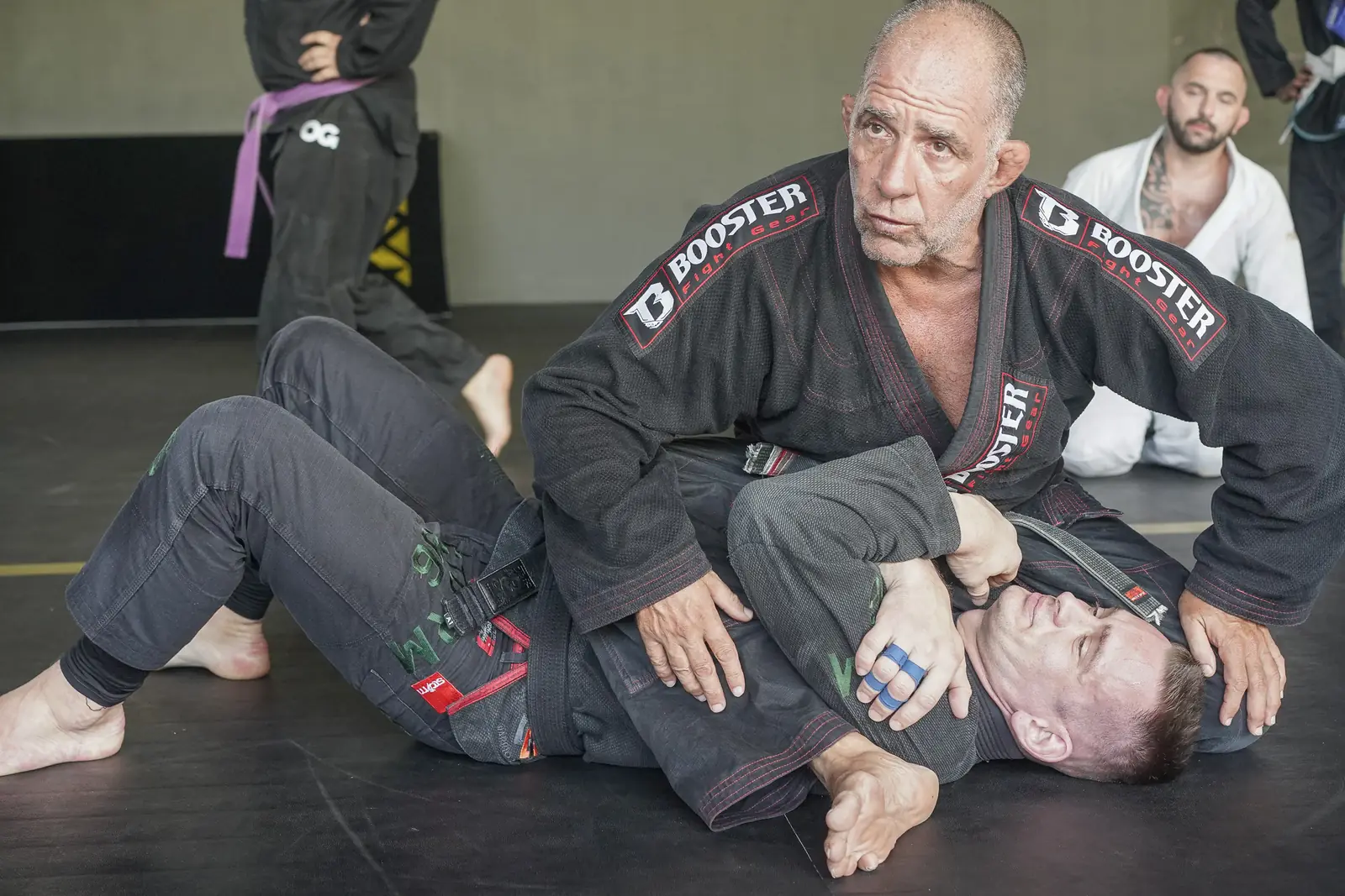 Professor Olavo Abreu in a black gi demonstrates a top position on a student while the seminar watches