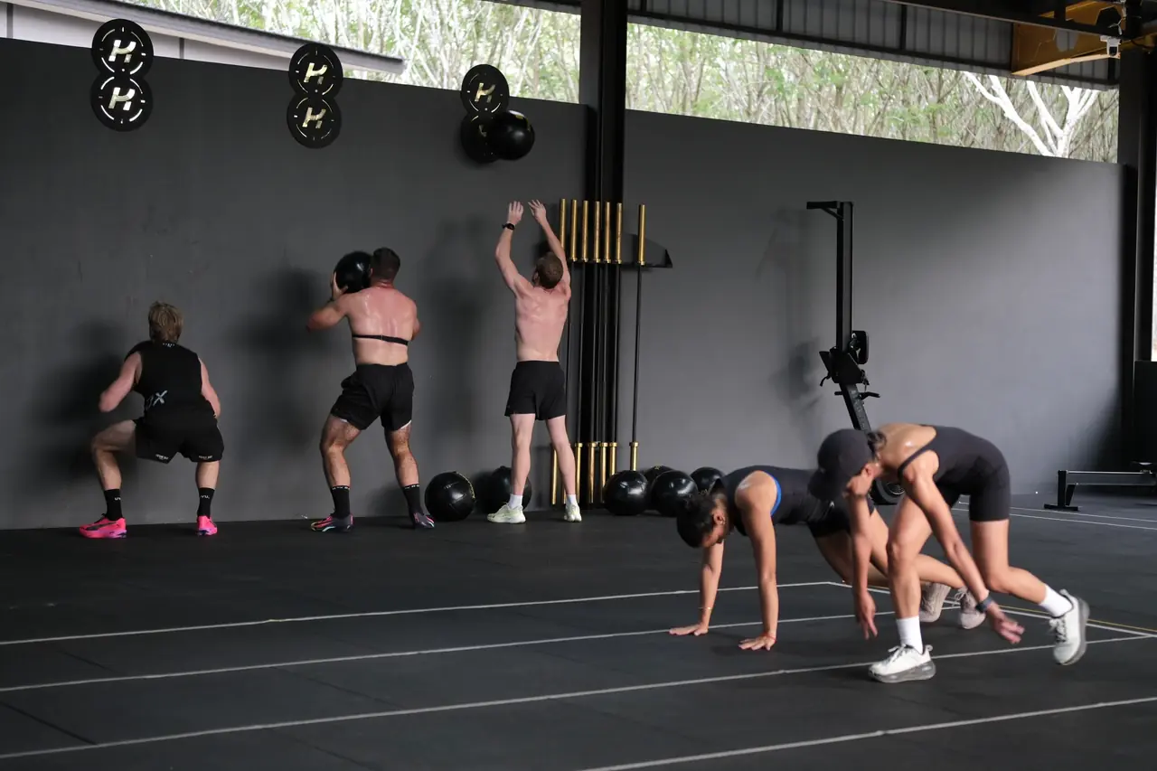 A HYROX class works through wall balls and burpees together on the fitness floor