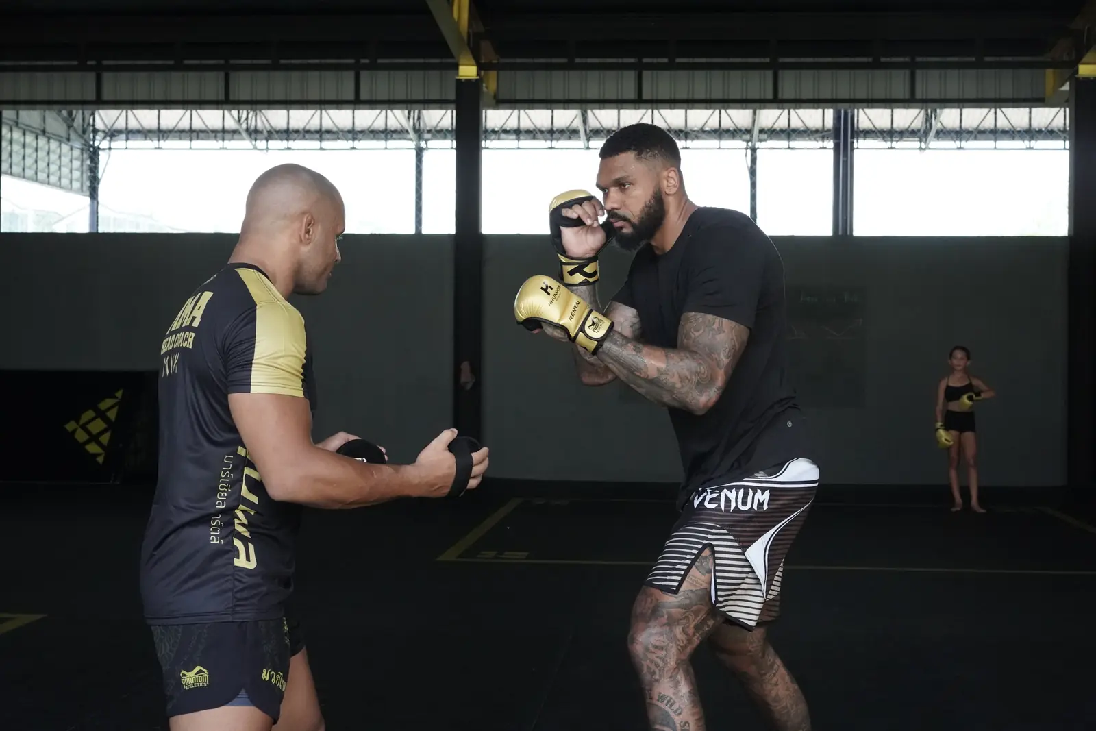 Khunpon's MMA head coach holds pads for a fighter in a one-to-one session on the mats