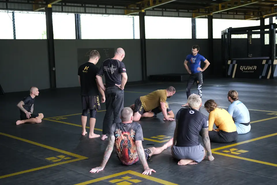 Participants sit in a circle on the mat listening