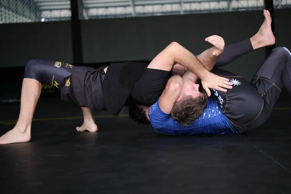 A participant works from guard against a partner in blue