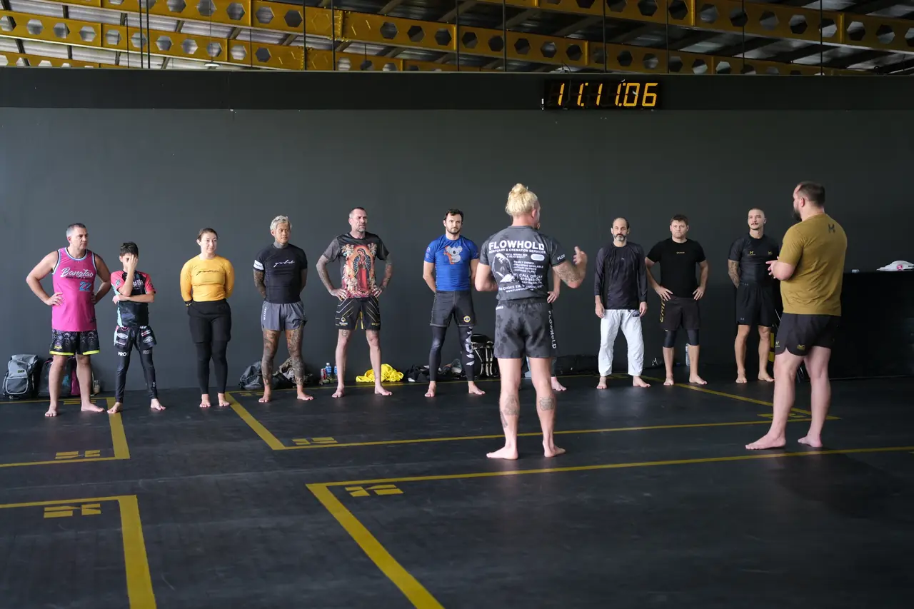 Participants in rash guards line up along the mat as the seminar begins