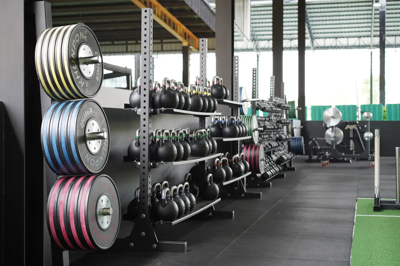 Racks of coloured bumper plates and rows of kettlebells in the Khunpon strength area