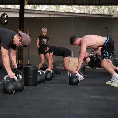 Members pick up kettlebells for a farmer's carry