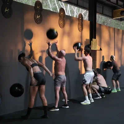 A HYROX class throwing wall balls