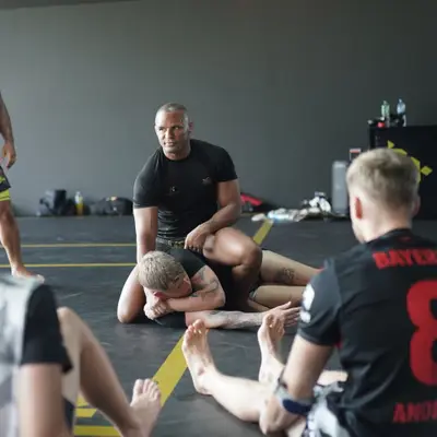 A coach demonstrates a ground position as the class watches